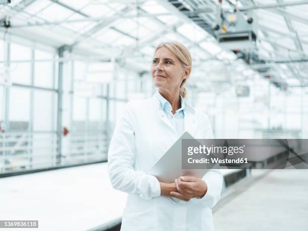 thoughtful scientist with tablet pc in industry - looking away stock-fotos und bilder