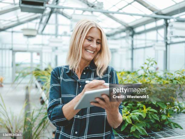 happy scientist using digital tablet in greenhouse - agriculture happy stockfoto's en -beelden