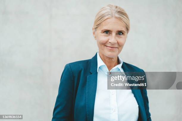 smiling businesswoman in front of wall - einzelne frau über 40 stock-fotos und bilder