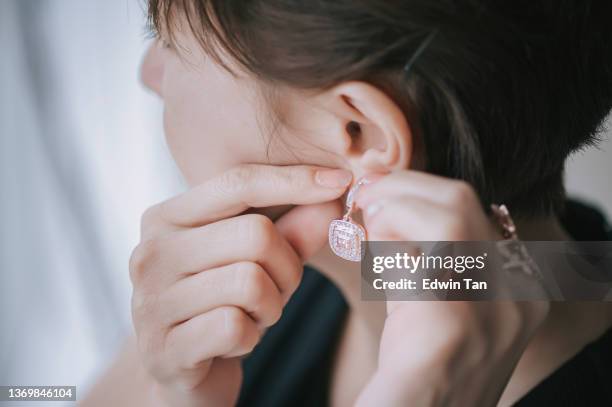 close up asian chinese woman put on earring jewelry - earring stock pictures, royalty-free photos & images