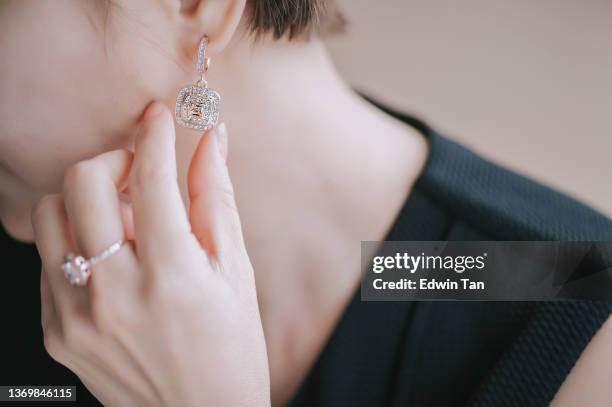 gros plan une femme chinoise asiatique met des bijoux de boucle d’oreille - anneau doreille couleur or photos et images de collection