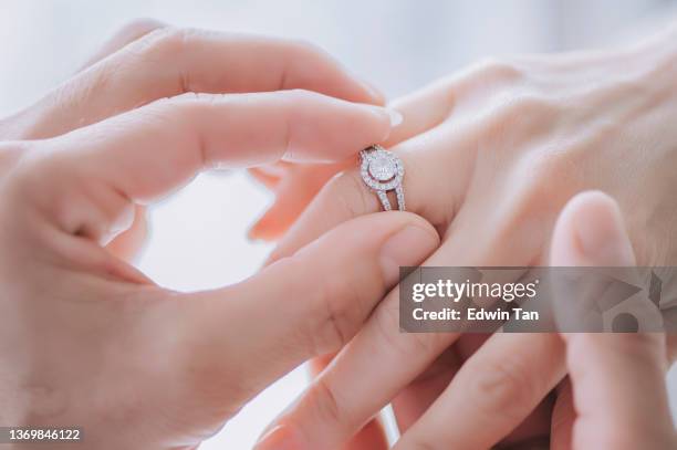 close up asian chinese newly wed couple hands with wedding ring - man holding engagement ring stock pictures, royalty-free photos & images