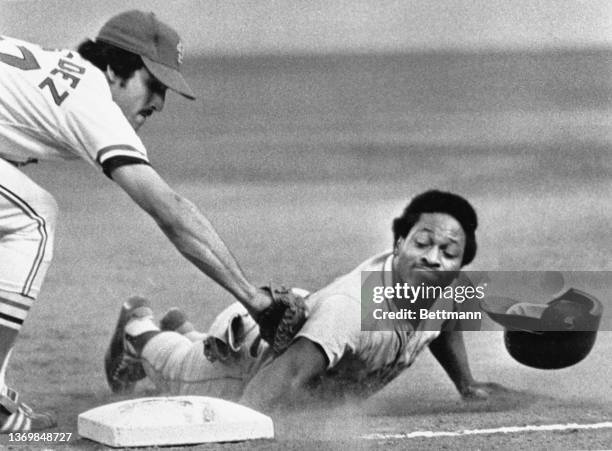 New York Mets' Lenny Randle loses his helmet as he dives back into first under the tag of St. Louis Cardinals' Keith Hernandez in the first inning....