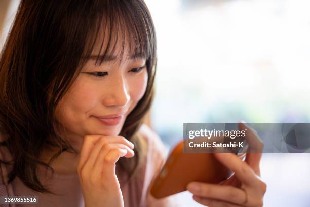 woman watching movie on smart phone in cafe - smartphone video stock pictures, royalty-free photos & images