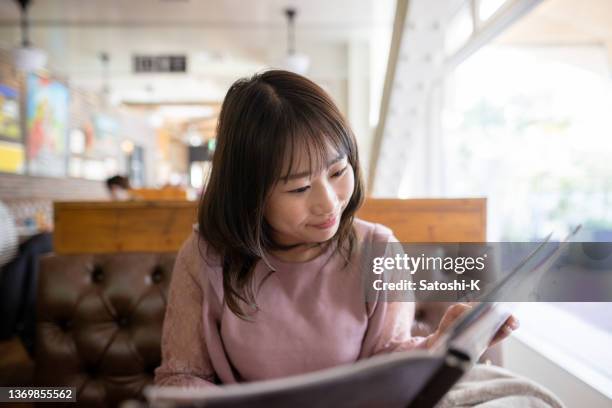 woman looking at menu for lunch in restaurant - 薄ピンク stockfoto's en -beelden