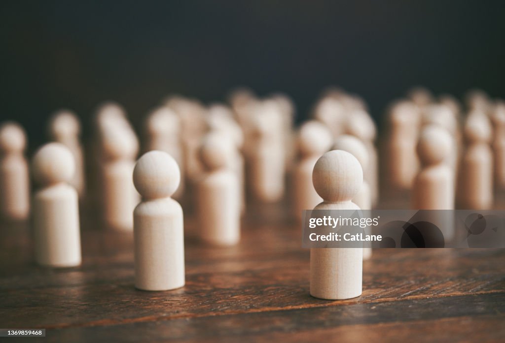 Collection of generic people-shaped wooden shapes to represent conformity and crowds