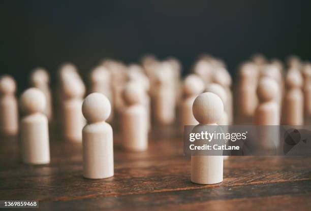 collection of generic people-shaped wooden shapes to represent conformity and crowds - crowdfunding stock pictures, royalty-free photos & images