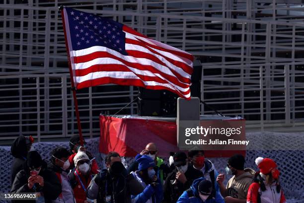 An American Flag flies behind Team USA members during the Women's Super-G on day seven of the Beijing 2022 Winter Olympic Games at National Alpine...