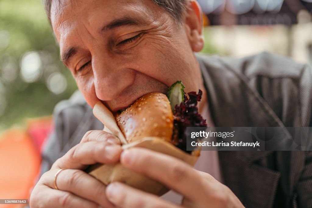 Sitting in fast food restaurant, man has snack