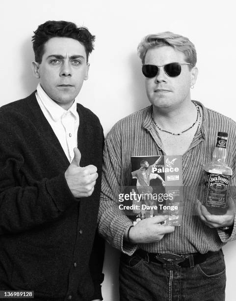 Comedians Sean Hughes and Eddie Izzard pose for a studio portrait, London, 1994. Izzard is holding a bottle of Jack Daniel's and a Crystal Palace FC...