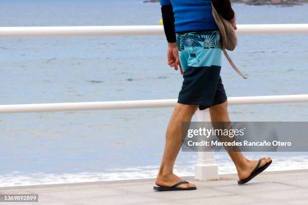 young man walking on the sidewalk by the beach. - thong stock pictures, royalty-free photos & images