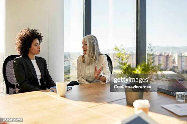 geschäftsfrauen diskutieren ideen im corporate office - two people talking face to face stock-fotos und bilder