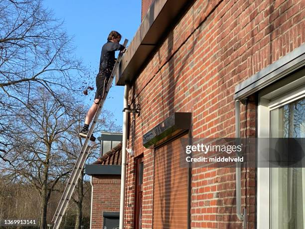 junger mann putzt die dachrinne - leaf on roof stock-fotos und bilder