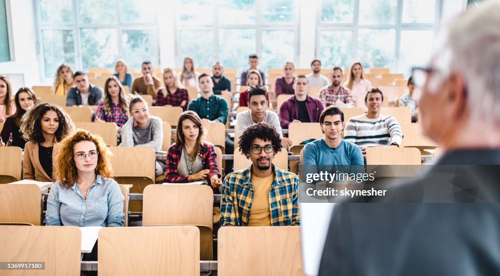 Large group of college students listening to their professor on a class.