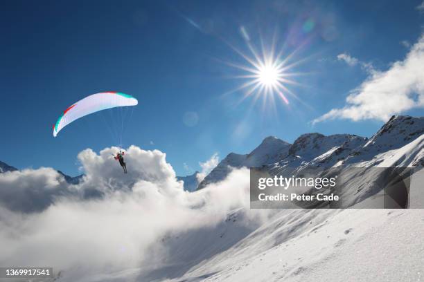 paraglider flying above the swiss alps - chute ski fotografías e imágenes de stock