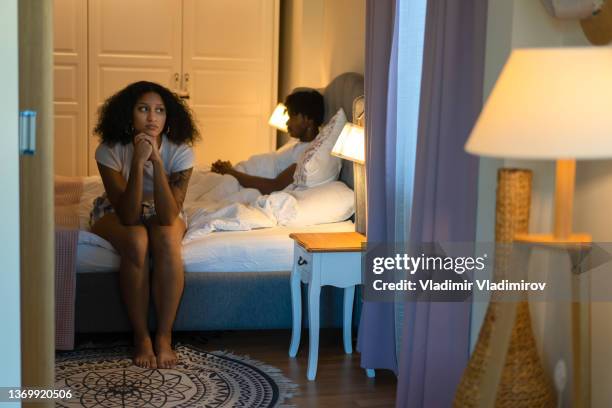 woman sitting on side of a bed - bed conflict stock pictures, royalty-free photos & images