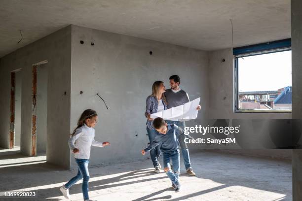 famiglia felice che analizza i piani nel loro nuovo appartamento - house shifting foto e immagini stock