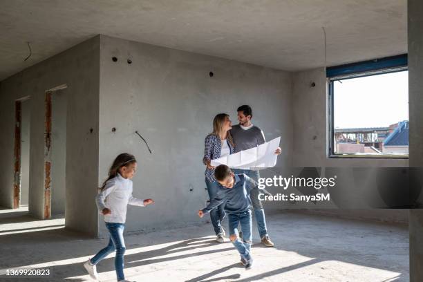 happy family analyzing plans at their new apartment - renovatie stockfoto's en -beelden