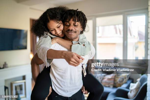 giving a piggyback ride to his girlfriend - young couple moving house stock pictures, royalty-free photos & images