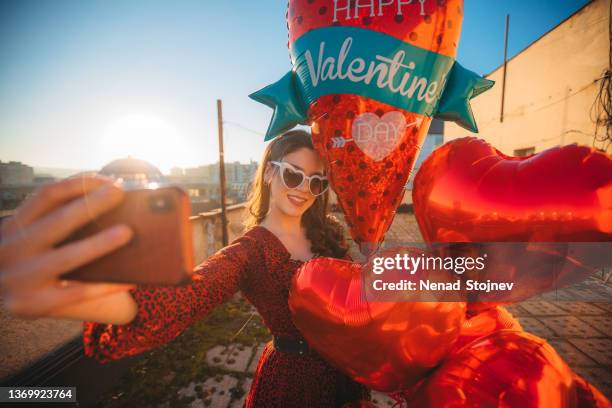 eine schöne frau macht selfies und hält heliumballons in der hand - helium stock-fotos und bilder