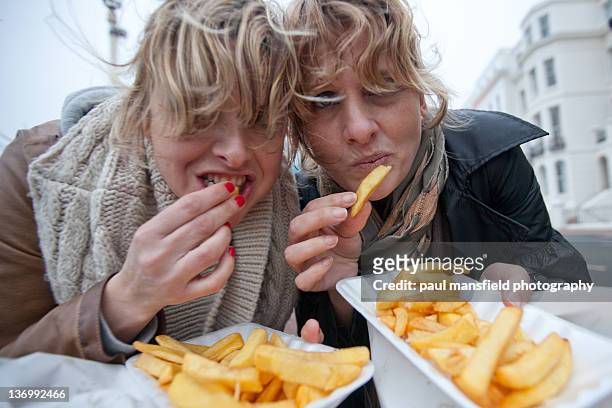 sisters eating chips - snapshot of britain fotografías e imágenes de stock