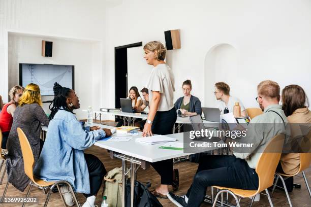 teacher talking to one of her students during seminar - onderwijsinstituten en organisaties stockfoto's en -beelden