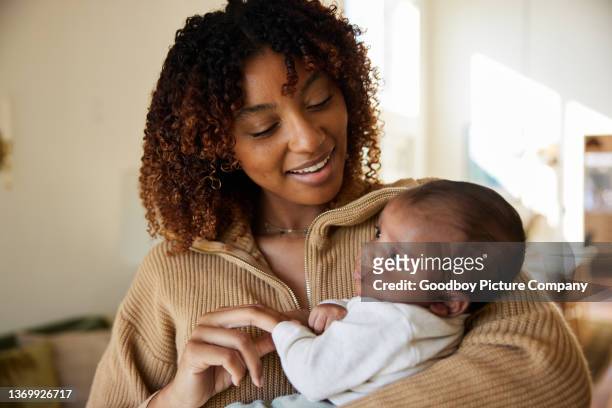 lächelnde mutter, die zu hause mit ihrem kleinen sohn im arm steht - cute black newborn babies stock-fotos und bilder
