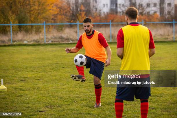 kaukasische männliche fußballspieler mit einem fußballtraining im freien - fussball pass stock-fotos und bilder