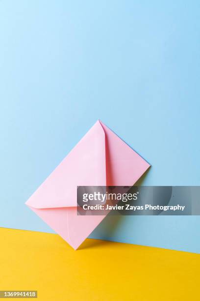 closed pink envelope on a blue and yellow background - correspondence stockfoto's en -beelden