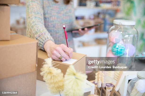 woman hands writing on paper working with digital tablet in organic store - homemade soap stock pictures, royalty-free photos & images