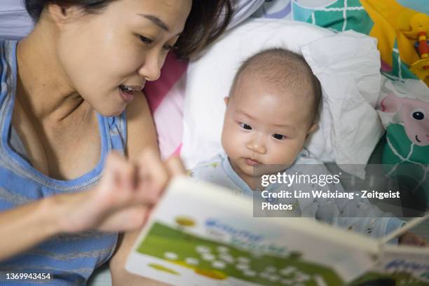 asian mum reading bedtime story to baby - bedtime stock pictures, royalty-free photos & images