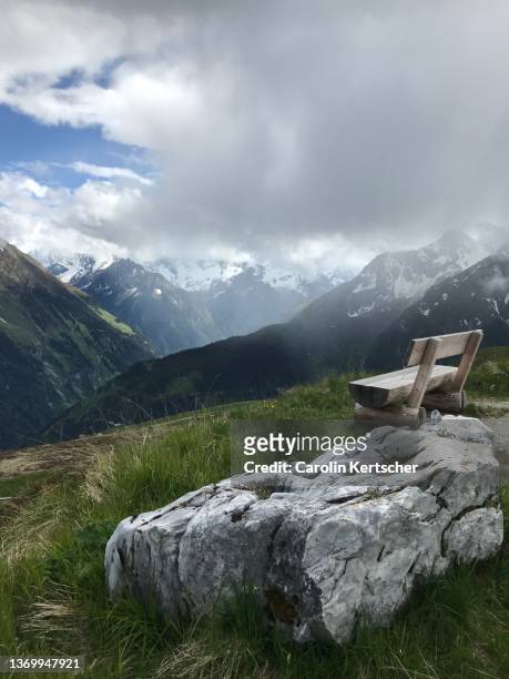 wooden bench on a hill with view of rain clouds in the zillertal alps | austria - alpes de zillertal fotografías e imágenes de stock