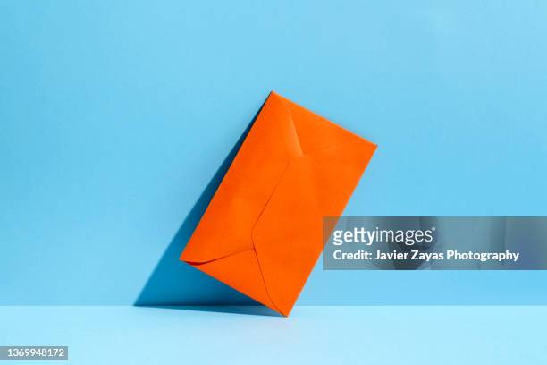 closed orange envelope on blue colored background - post stock-fotos und bilder