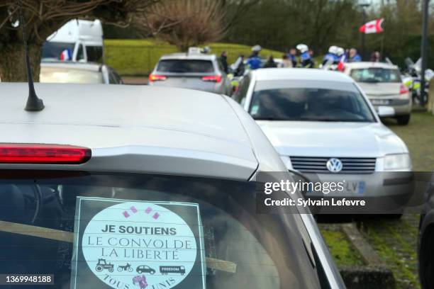 Policemen and French anti-COVID restrictions protesters are seen close to a sticker on a car rear windowshield reading "I support Freedom Convoy" as...