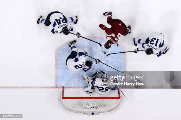 Kaspars Daugavins of Team Latvia is challenged by Hannes Bjorninen, Valtteri Kemilainen and Ville Pokka of Team Finland in the first period during...