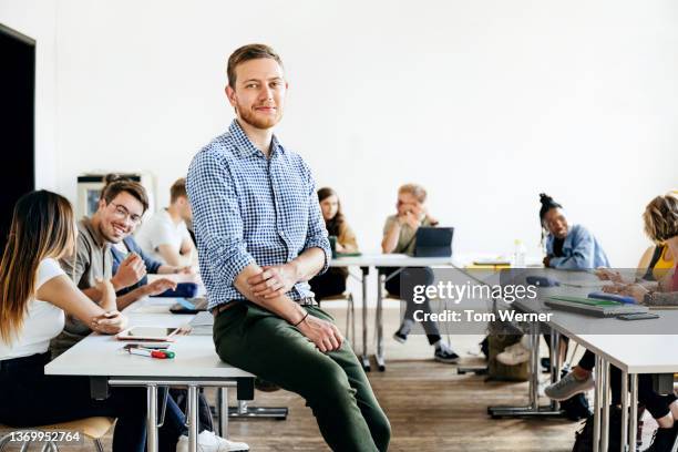 portrait of seminar tutor leaning on desk in class - teachers white university stock pictures, royalty-free photos & images