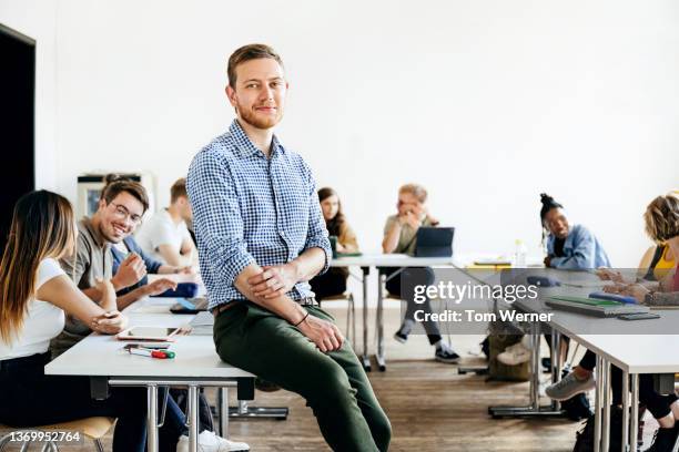 portrait of seminar tutor leaning on desk in class - portrait of teacher and student bildbanksfoton och bilder