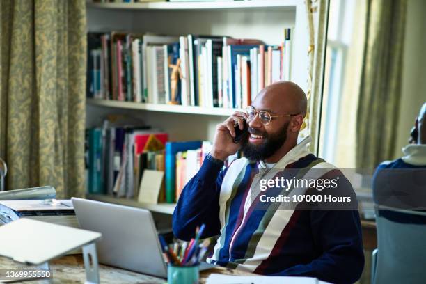 cheerful relaxed businessman on phone in home office with laptop - one mid adult man only stock pictures, royalty-free photos & images