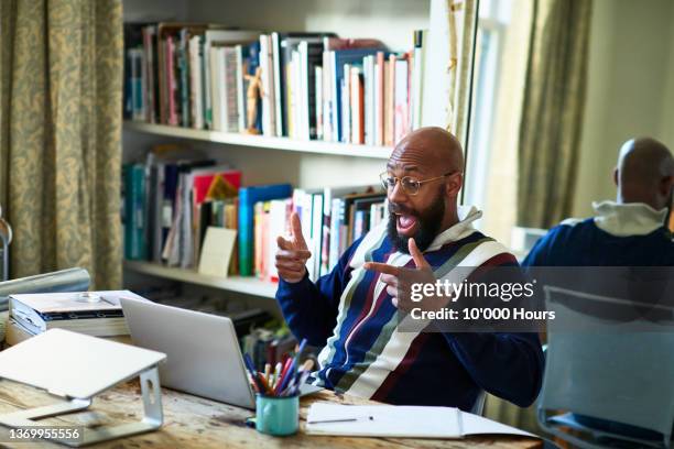 surprised black businessman on video conference call in home office - excitement photos et images de collection