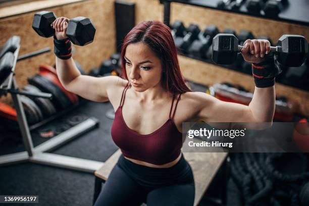 redhead woman exercising with dumbbells - women's weightlifting stock pictures, royalty-free photos & images