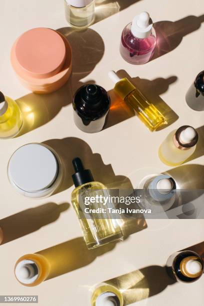 glass bottles for cosmetic products with pipette, natural skincare face cream and essential oil on beige background. beauty products. multitasking beauty, skinmalism, skin care concept. - kosmetikprodukte stock-fotos und bilder