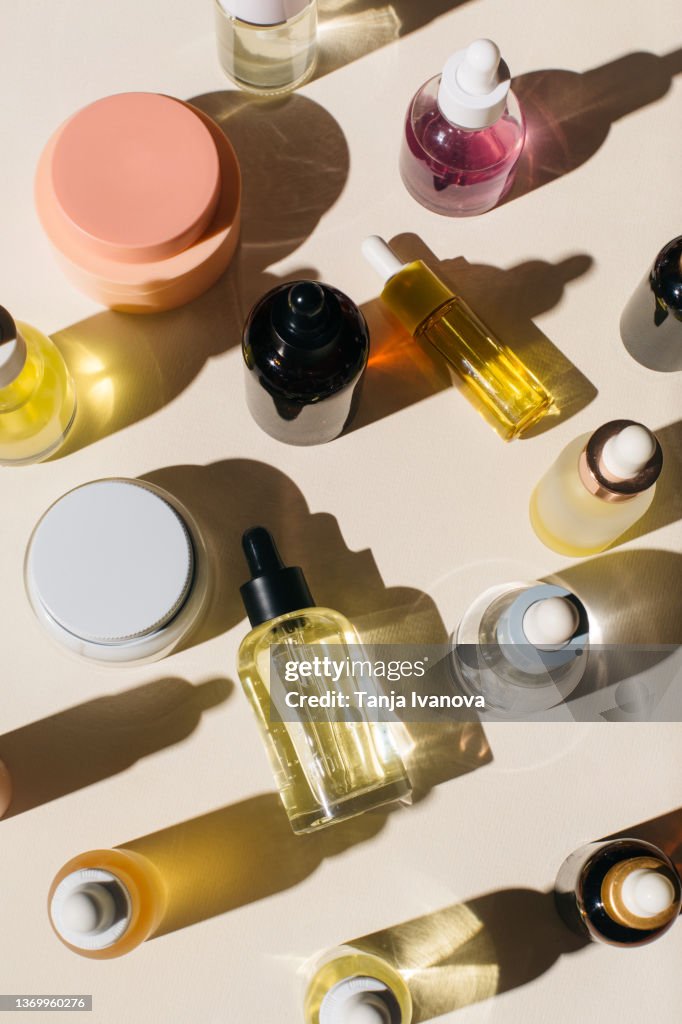 Glass bottles for cosmetic products with pipette, natural skincare face cream and essential oil on beige background. Beauty products. Multitasking beauty, skinmalism, Skin care concept.