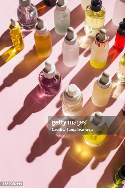 glass bottles for cosmetic products with pipette, natural skin care and essential oil on pink background. beauty products. skin care concept. - argan oil stock-fotos und bilder