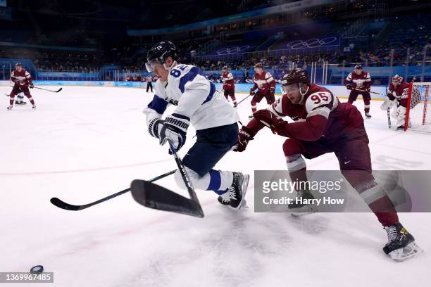 Harri Pesonen of Team Finland is challenged by Oskars Batna of Team Latvia during the Men's Ice Hockey Preliminary Round Group C match on Day 7 of...