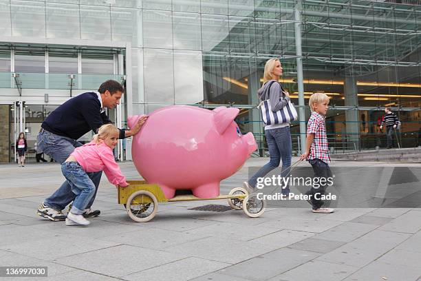 family walking in town with giant piggy bank - couple saving piggy bank ストックフォトと画像