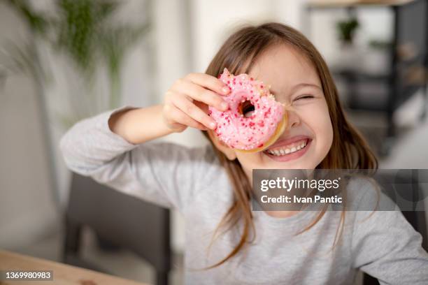 retrato de cerca de una feliz chica caucásica tomando un postre de pastelería en casa - buñuelo en forma de rosca fotografías e imágenes de stock
