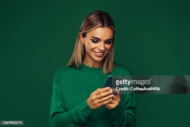 linda mulher emocional segurando telefone inteligente - vestido verde - fotografias e filmes do acervo