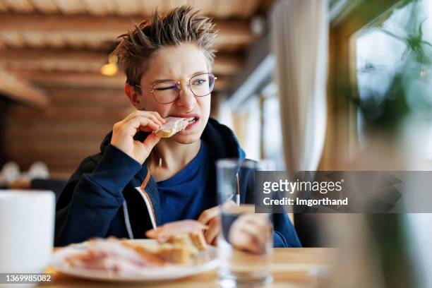 teenage boy eating a very tough sandwich - hungry teen stock pictures, royalty-free photos & images