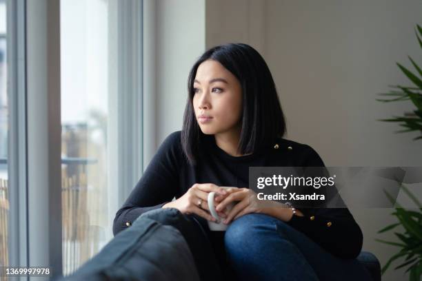 donna che beve caffè vicino alla finestra di casa - introspection foto e immagini stock