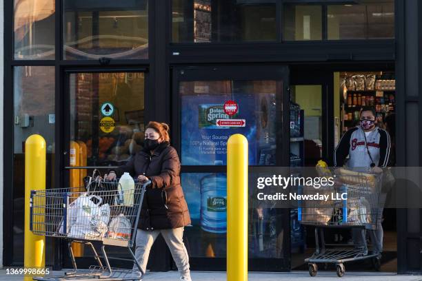 Customers wearing masks push shopping carts as they leave Compare Foods supermarket in Patchogue, New York, on February10, 2022.